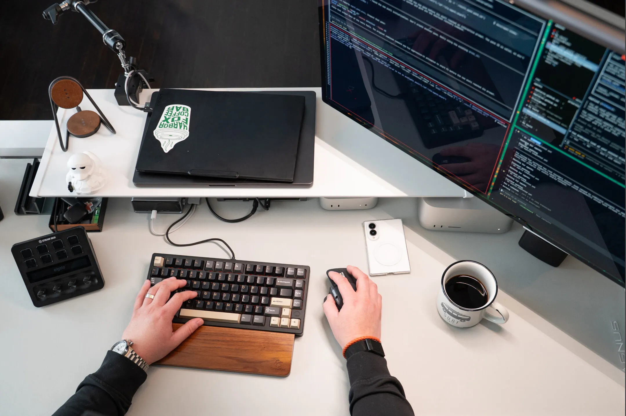 Overhead view of Damian's desk: mechanical keyboard, a monitor full of code, and a coffee